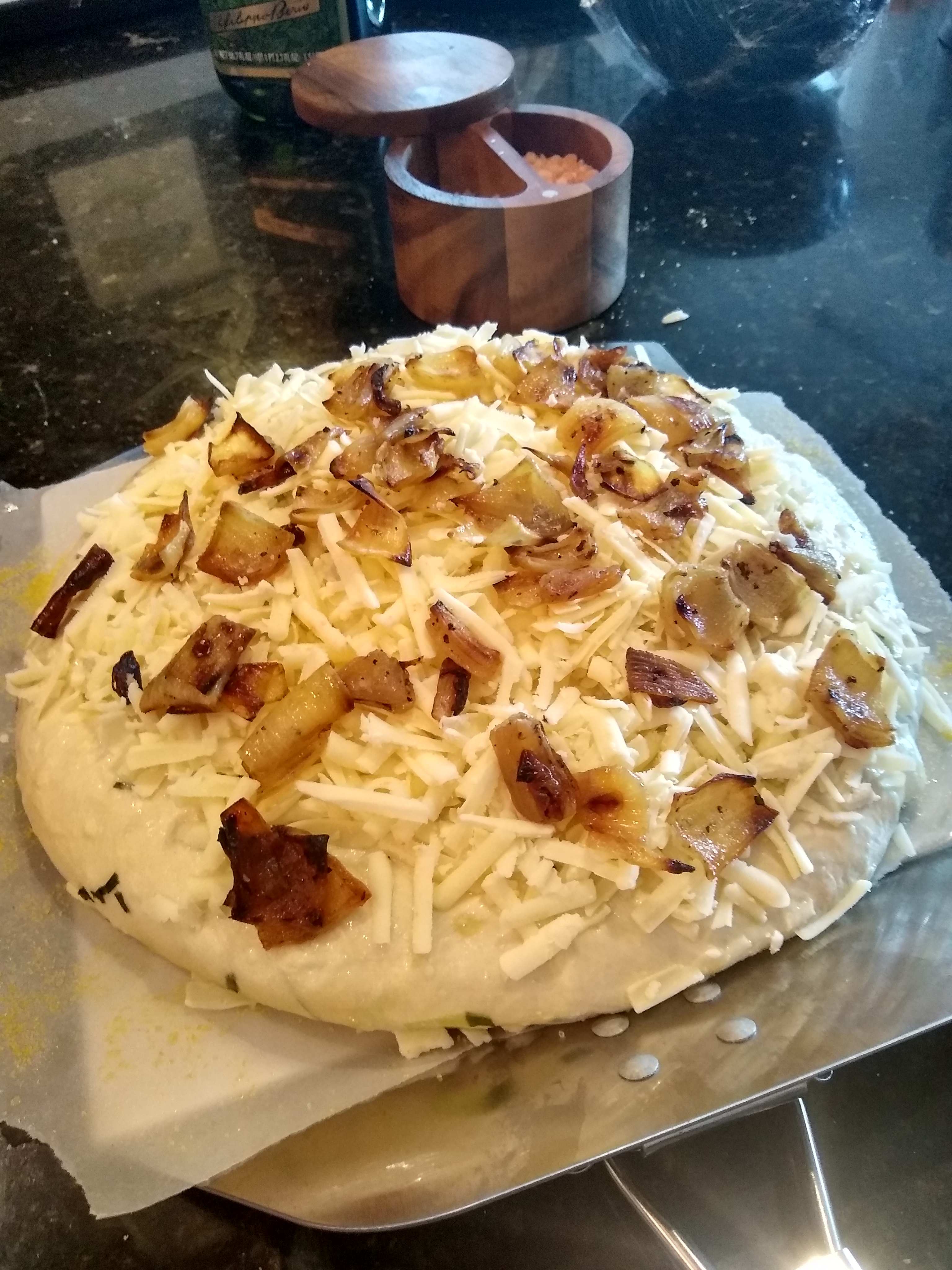 Dough ready for the oven.  Topped with asiago cheese and roasted onions.